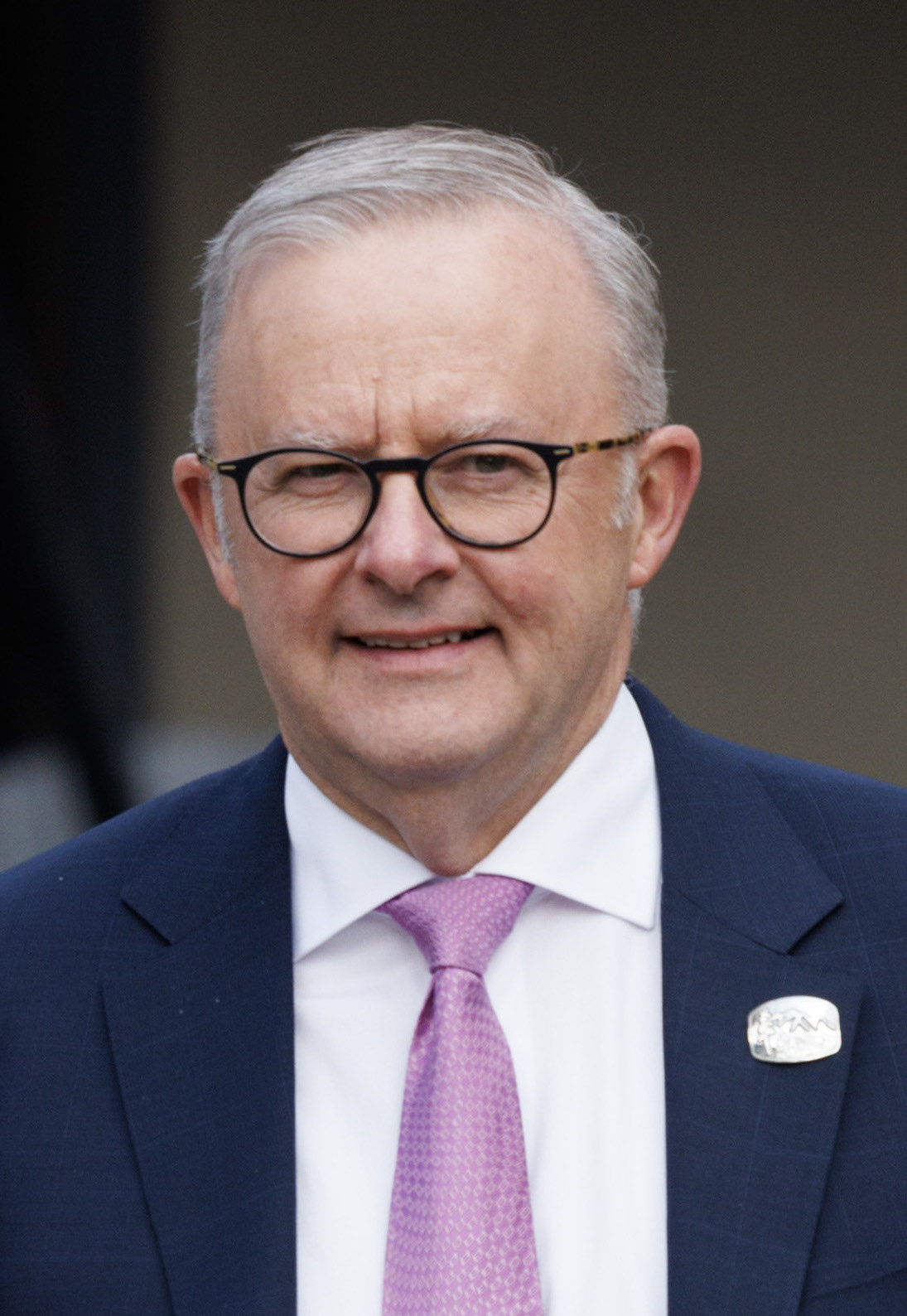 Head-and-shoulders photo of Anthony Albanese, a grey-haired man with dark-rimmed glasses, a navy suit and a lilac tie
