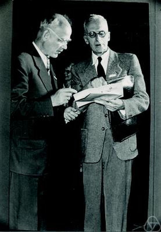 Black-and-white photo of two older men in suits reading papers together; Ott-Heinrich Keller is on the left