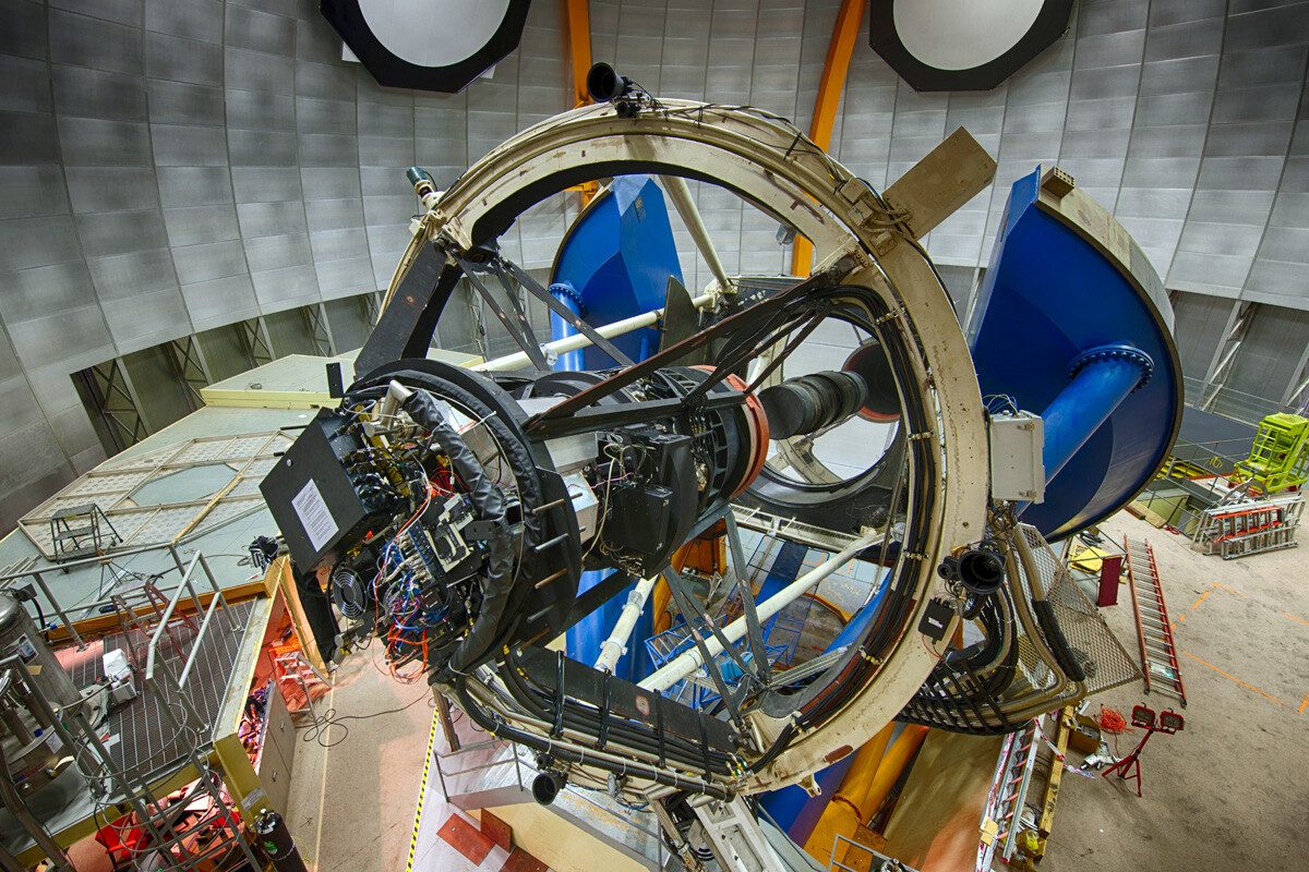 The Blanco telescope inside its dome, with the black Dark Energy Camera mounted at the top of the white truss and a large blue bearing below