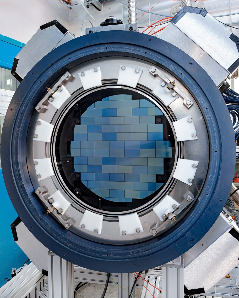 The circular front of the Dark Energy Camera, showing a mosaic of rectangular blue CCD sensors inside a large metal ring