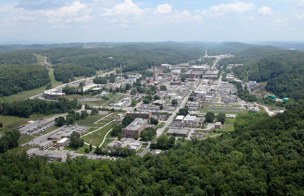 Aerial view of a large laboratory campus with office buildings, parking lots and wooded hills