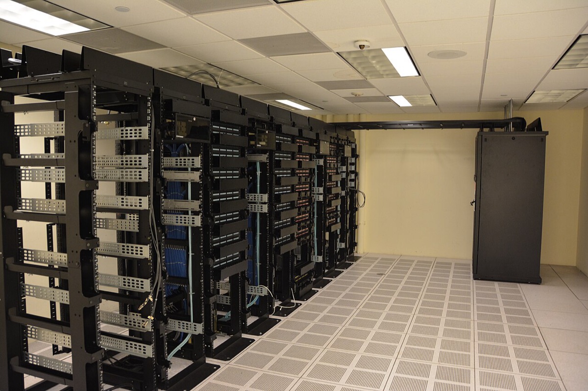 Rows of black server racks in a data center with tiled flooring
