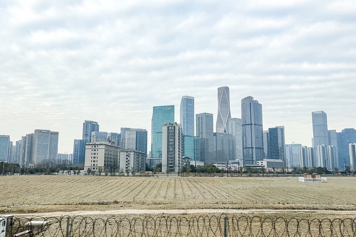 The Hangzhou skyline across a field, with glass towers in the distance