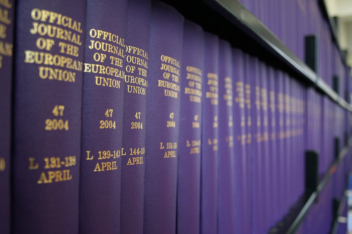 Rows of bound volumes of the Official Journal of the European Union on a library shelf, purple covers with gold lettering