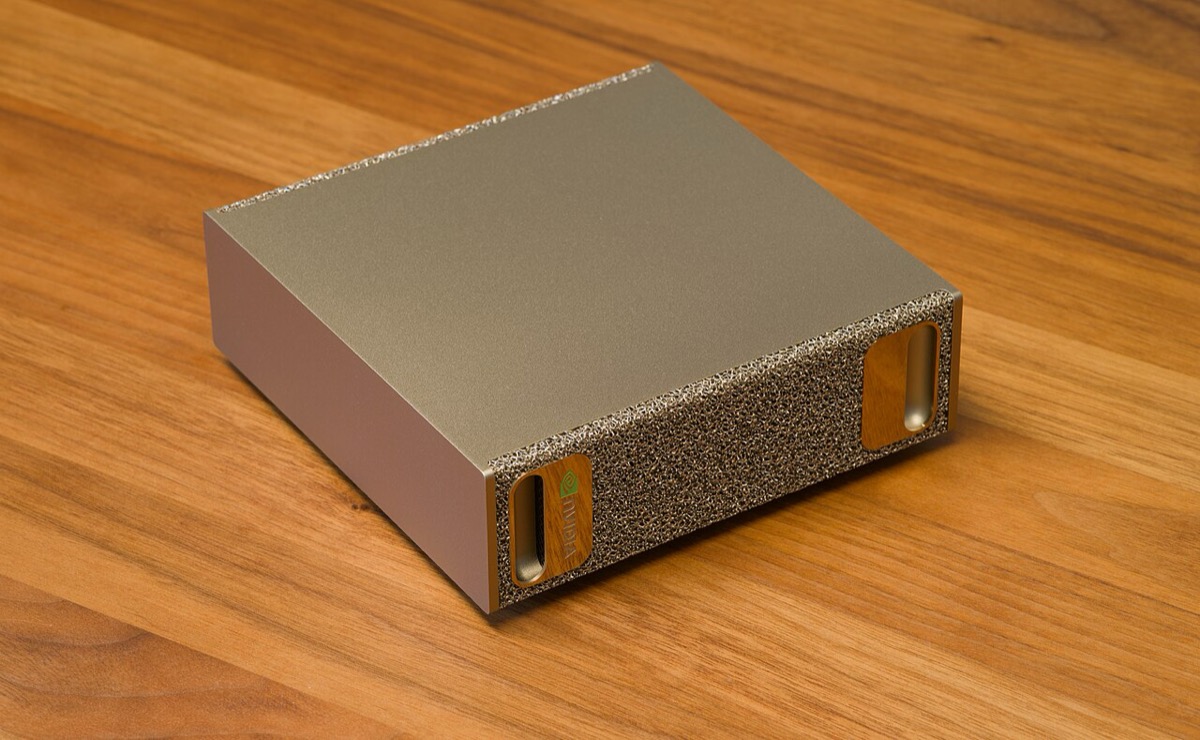 A small, square, gold-colored desktop computer photographed at an angle on a table