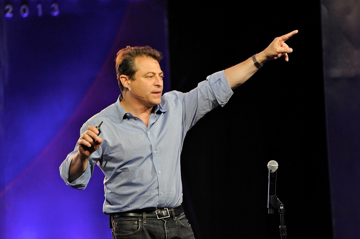 Peter Diamandis, in a dark suit, speaking on stage with a microphone