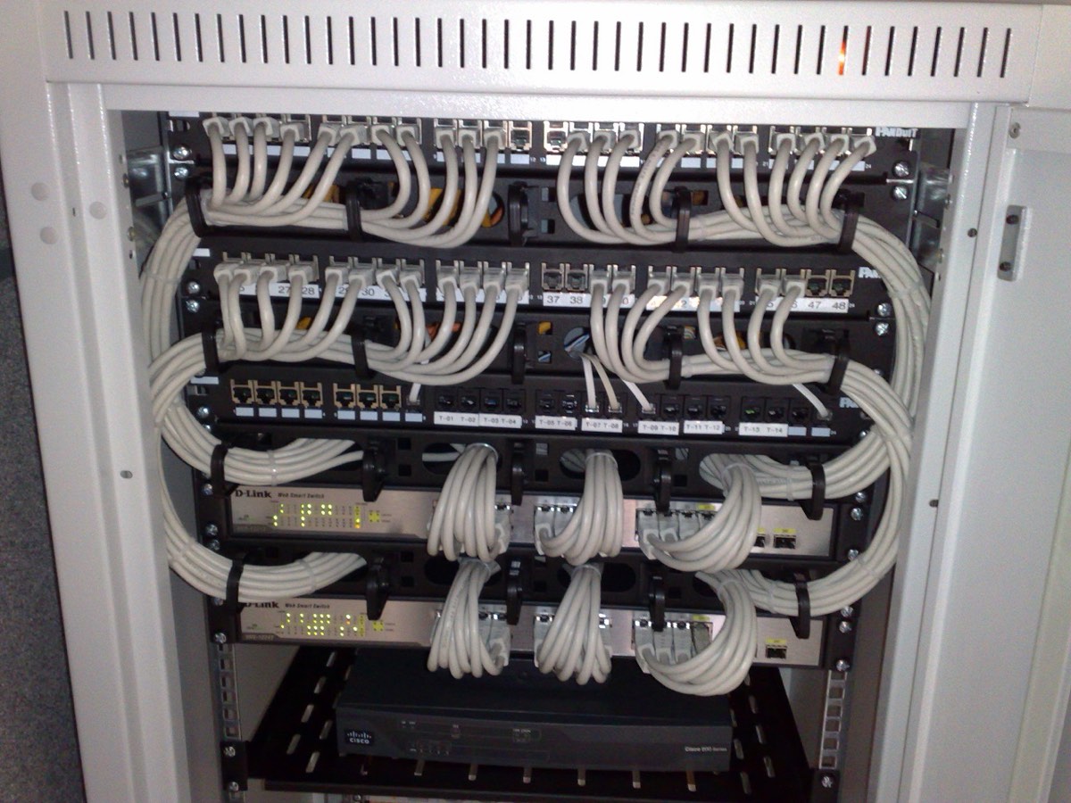 A network rack with two Ethernet switches and patch panels connected by neatly bundled gray patch cables