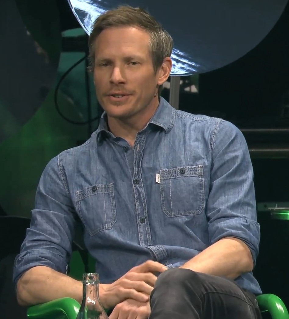 Thomas Wolf seated on a stage in a denim shirt, speaking during a panel