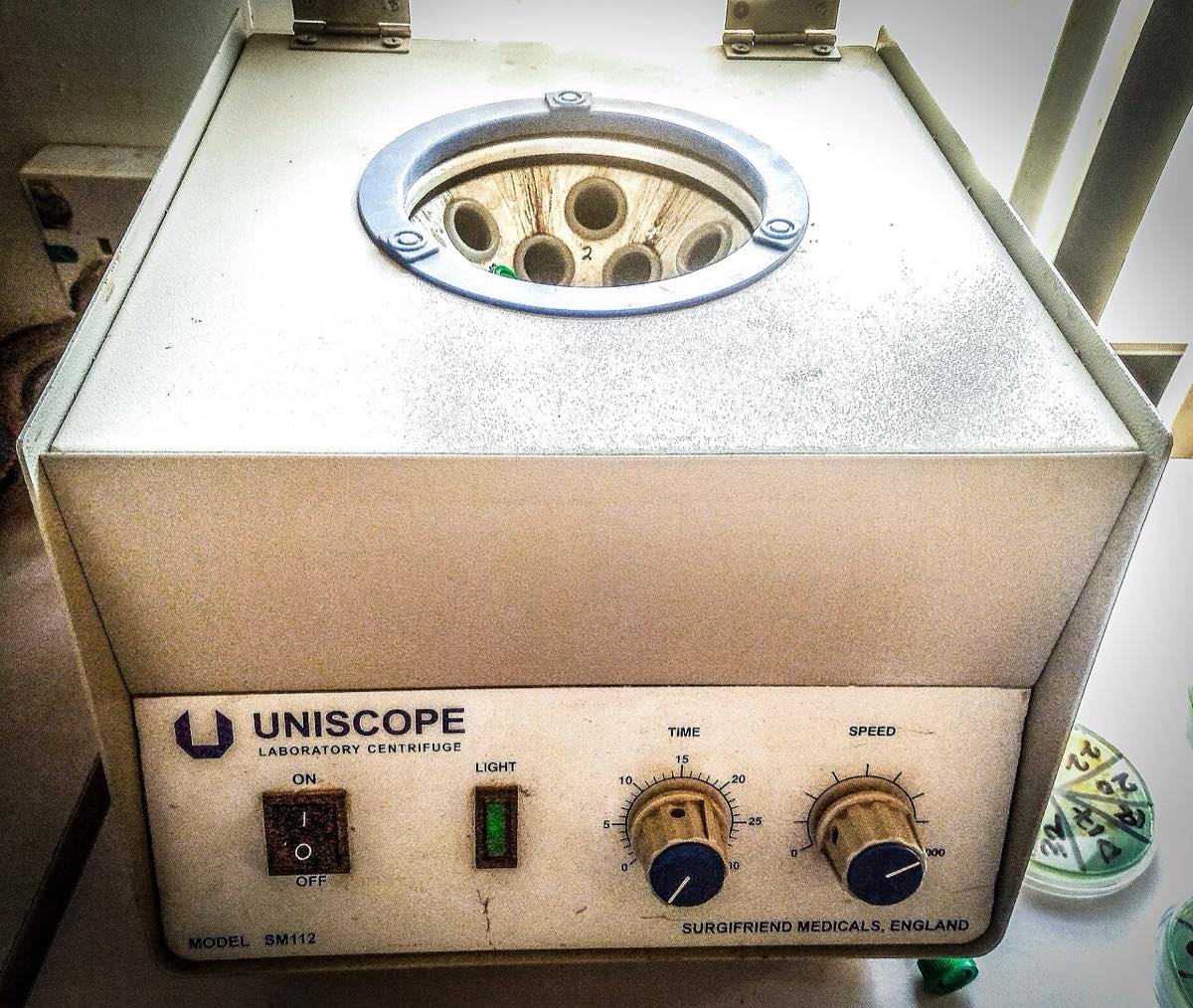 A benchtop laboratory centrifuge with its lid open, showing a rotor that holds sample tubes