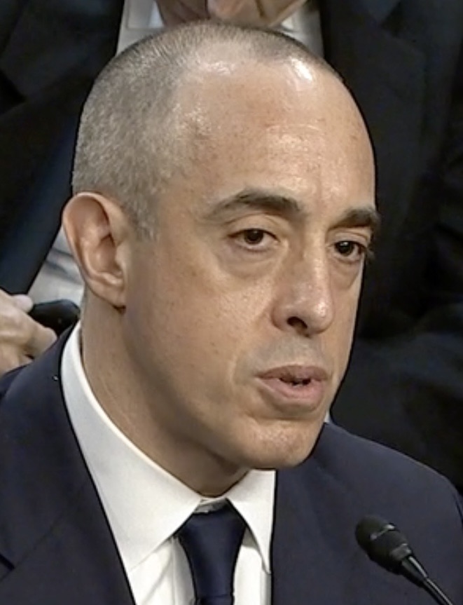 Emil Bove, a man with closely cropped grey hair in a dark suit and tie, speaking at a hearing