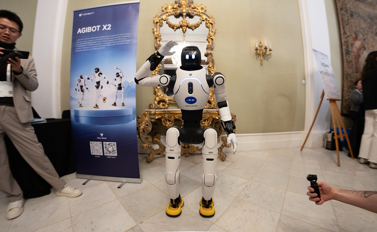 A white and black humanoid robot raising one hand in a room with an ornate gold mirror, next to a product banner